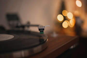turntable with record to play music. Cozy vintage ambience at home. Lights bokeh on holiday season  