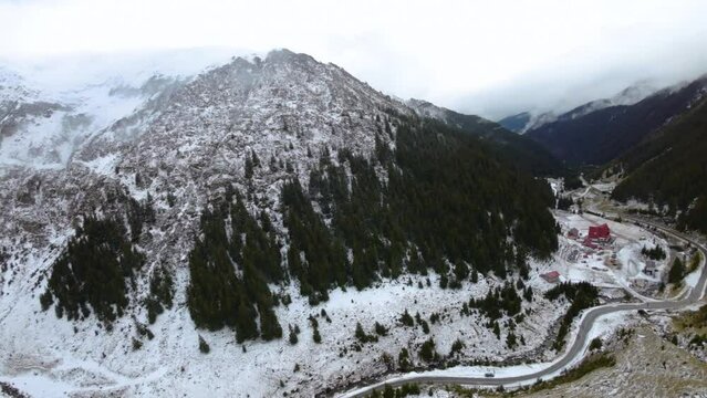  Aerial view of a mountain road in Fagaras mountains in Romania. Transfagarasan, Hotel Capra. Early winter season. Road closed in winter at the first snow. Mountain forest road covered with snow. 