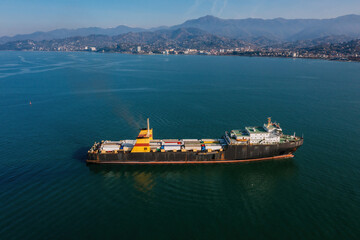 Cargo ship with containers and trucks, aerial drone view