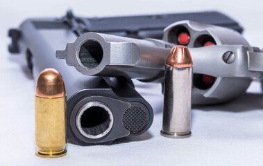 Two handguns, a 45 caliber pistol and a 44 special revolver with a bullet for each next to it on a white background