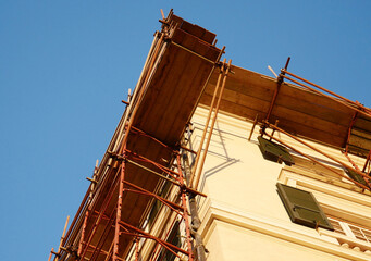 Scaffolding with wooden planks on the corner of a building under renovation