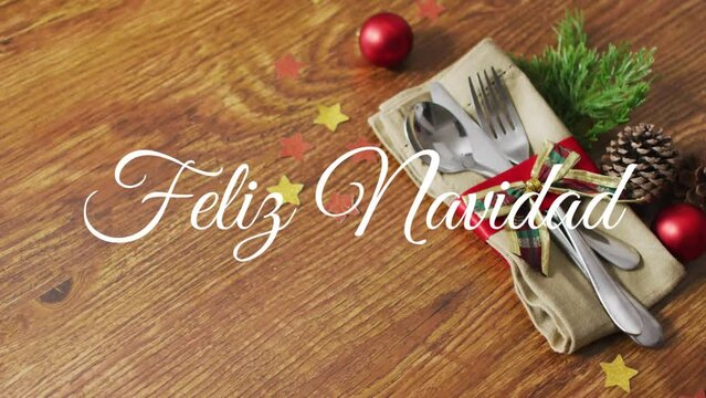 Animation of feliz navidad text over christmas cutlery and decorations