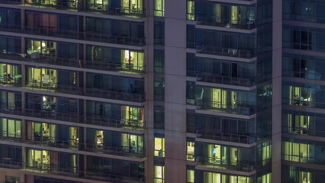 Windows lights in residential high-rise buildings timelapse at night. Multi-level skyscrapers with illuminated rooms inside