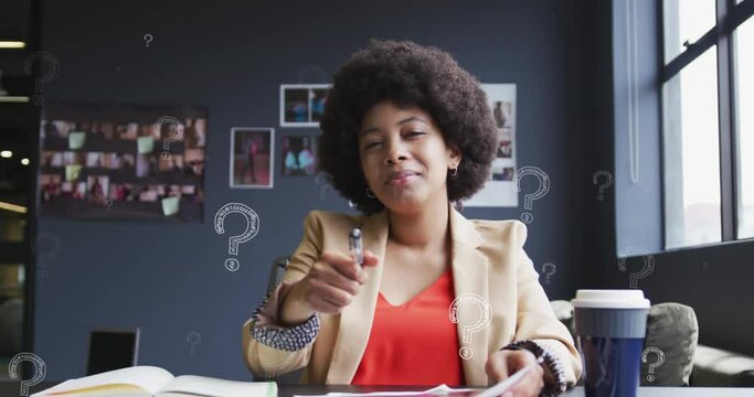 Animation of question mark symbol over biracial businesswoman with afro hair writing in book