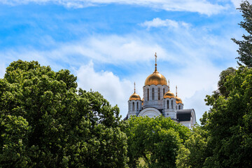 orthodox church among the trees against the sky with white smeared clouds