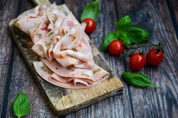 Slices Of  Traditional Italian antipasti mortadella on a wooden  cutting board