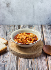 Tripe casserole on bottom and wooden spoon. Winter comfort food. (Callos a la madrileña)