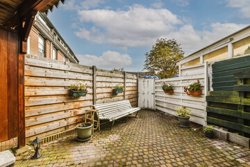a backyard area with a bench and potted planters on the side of the yard, surrounded by white clouds