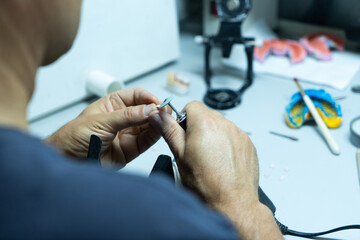 Dental technician works in his workshop and makes artificial teeth for dentistry. close-up.