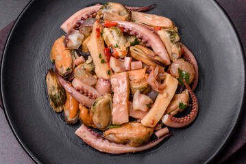 Delicious pickled seafood salad or cocktail on a black plate