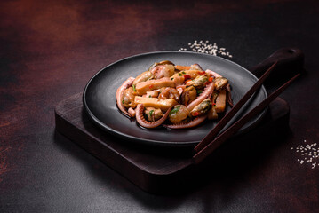 Delicious pickled seafood salad or cocktail on a black plate