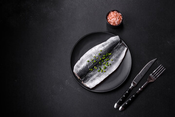 Marinated fillet with spices and herbs of sea herring on a black plate