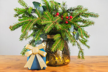 Christmas present and bouquet of fir branches in interior. Christmas still life.