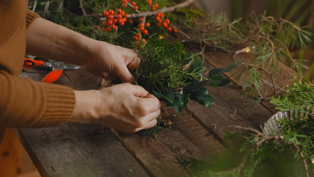 Female florist creating Christmas wreath in flower shop.