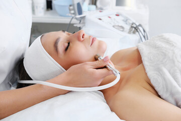 The cosmetologist makes the procedure Microdermabrasion of the skin of the face of a beautiful,...