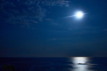 Fototapeta na wymiar moon on blue night over sea with light reflection and clouds in the dark sky, puerto escondido oaxaca 
