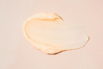 Silky cosmetic cream texture. Cream or body butter smear over pastel beige background. Skincare product smudge
