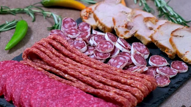Meat plate with assortment of various tasty Spanish, french or Italian appetizers - sliced prosciutto, sausage, salami, kabanos sausages, fuet. Meat platter rotating