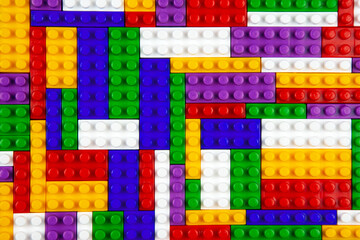 Abstract background texture of colored constructor blocks. Background of colorful plastic part of constructor. Pile of colored toy bricks.