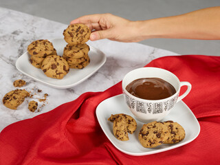 Hand picking up a chocolate cookie and cup with hot chocolate