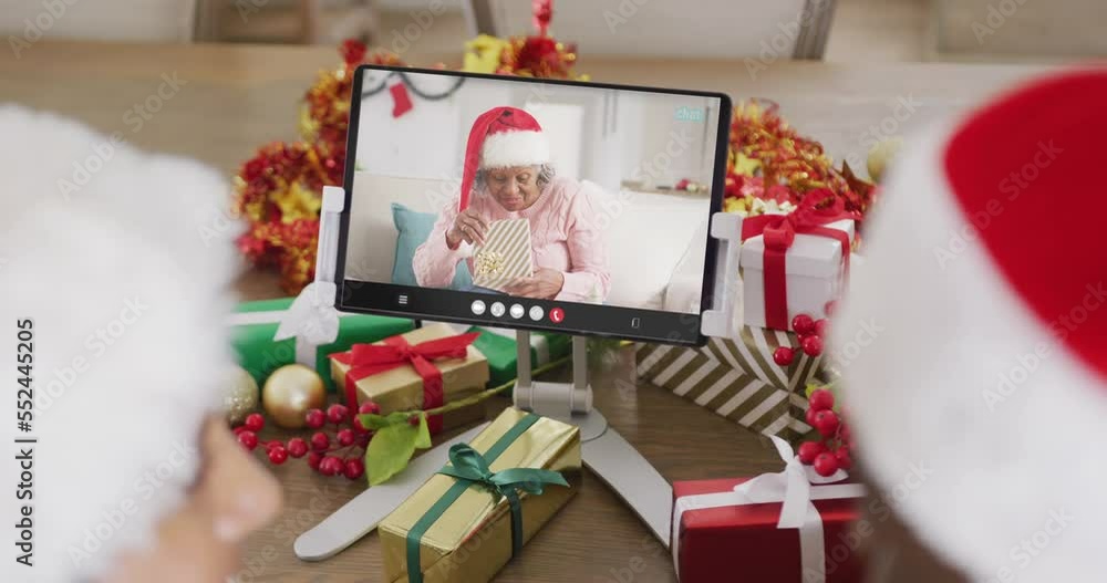 Wall mural Diverse couple with santa hats having tablet video call with african american woman