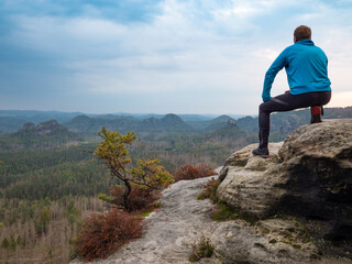 Man sitt on cliff edge and looking to rising sun above  valley