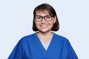 Smiling middle aged female nurse in blue uniform looking at camera
