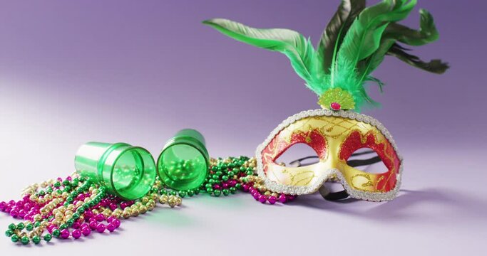 Video of carnival masquerade mask with green feathers, mardi gras beads and shot glasses, copy space