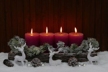 Advent und Weihnachtsdekoration. Arrangement mit vier roten Kerzen und Weihnachtsschmuck im Schnee.