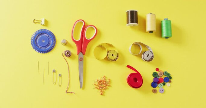 Video of tape measures, needles, pins, scissors, buttons and sewing threads on yellow background