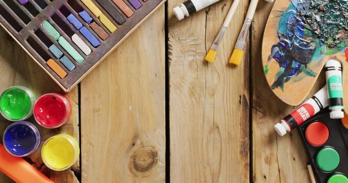 Video of paints, paintbrushes, palette and pastels on wooden boards with copy space