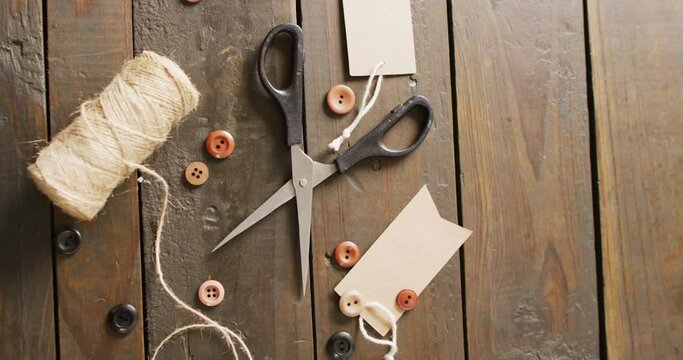 Video of scissors, twine string, buttons and gift tags on dark wood boards with copy space