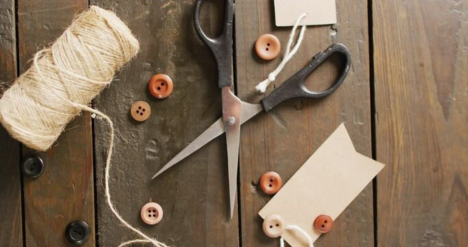 Video of scissors, twine string, buttons and gift tags on dark wood boards