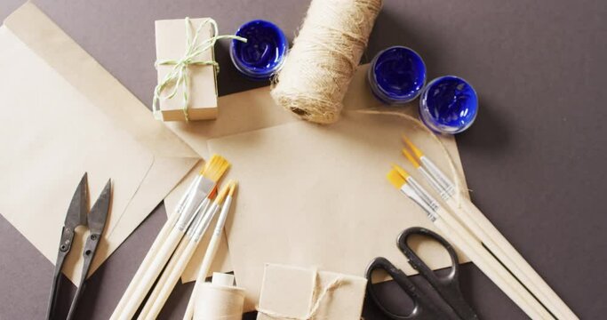 Video of parcels with twine, card, scissors, brushes and paint on grey background
