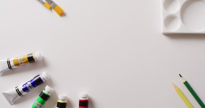 Video of tubes of water colour paint, paintbrushes and palette on white background with copy space