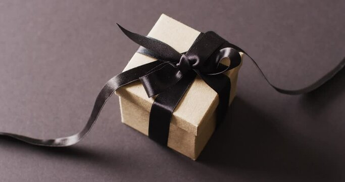 Video of gift box tied with black ribbon on dark grey background with copy space