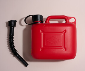 Red plastic canister for liquid fuels and lubricants on a beige background