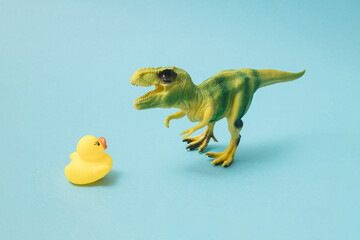 T-rex with yellow rubber duck on blue background.