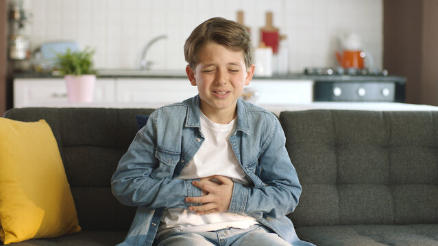 Little boy suffering from stomachache while sitting on sofa at home.The child has a stomach ache.