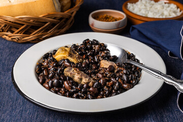 Beans and pork, in white plate with spoon. Typical food from Brazil.