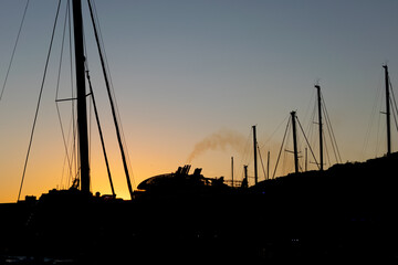 Silhouette of the ships during the sunset in the port. Pollution, emissions and waste. Concept of...