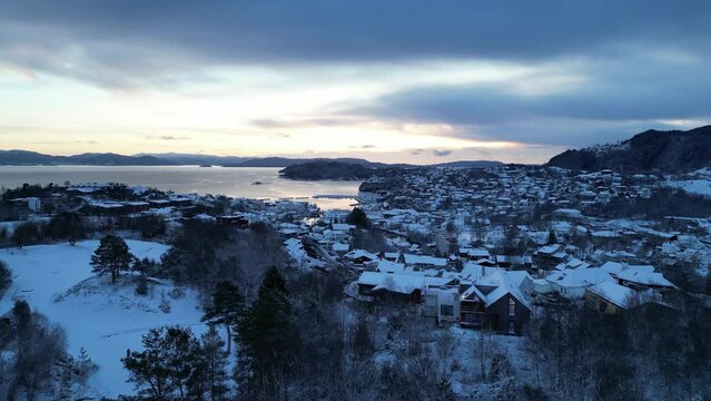 Flight toward the harbor of the coastal town of Os&oslash;yro, Bj&oslash;rnafjorden, Norway during winter. Sunset.