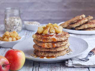 A plate of healthy rolled oat and apple pancakes topped with cooked diced apple pieces with sweet...