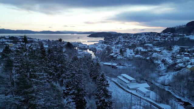 Flight toward the harbor of the coastal town of Os&oslash;yro, Bj&oslash;rnafjorden, Norway during winter. Sunset.