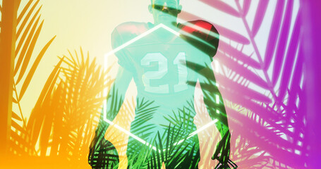 American football player wearing 21 number jersey standing by illuminated hexagon and plants