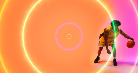 Naklejka premium Composite of biracial basketball player dribbling ball by illuminated multicolored circles