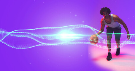 Naklejka premium Composite of biracial basketball player dribbling ball by wave pattern and lens flare, copy space