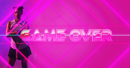 Biracial female athlete with racket standing by game over text and lines on pink background