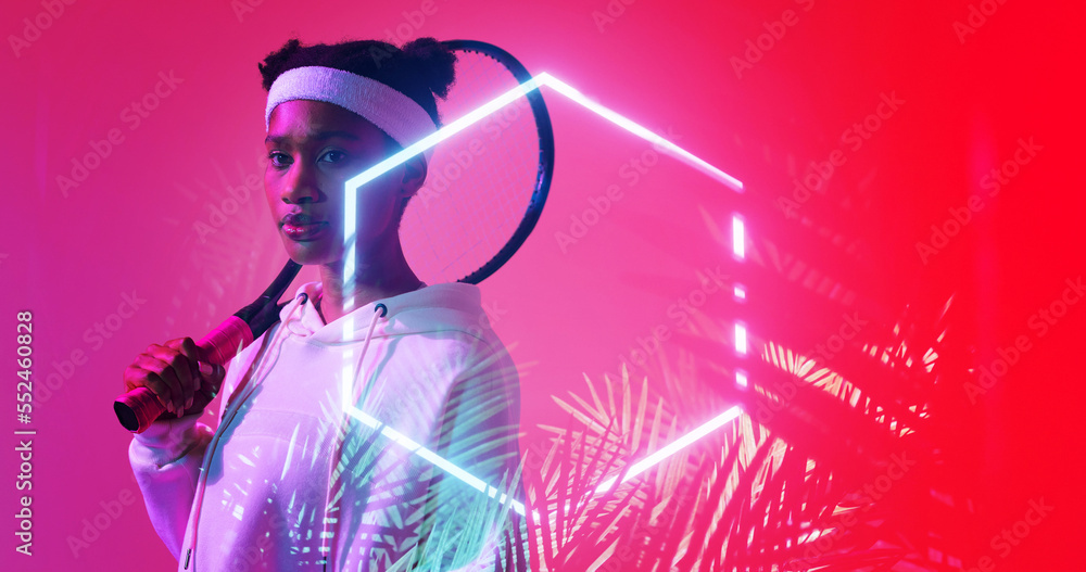 Poster biracial female player with racket standing by illuminated hexagon and plants on red background