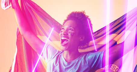 Cheerful biracial female soccer player with brazilian flag screaming over illuminated lines
